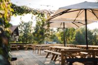 a row of picnic tables with umbrellas on a deck at Hotel Kaķītis in Sigulda