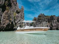 un barco en el agua frente a una montaña en Bahala Na Villas, en El Nido