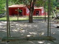 a swing in front of a red building with a tree at Pousada ZEN Cumuruxatiba in Cumuruxatiba