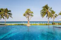 a swimming pool with palm trees and the ocean at Katathani Phuket Beach Resort - SHA Extra Plus in Kata Beach