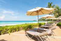 a row of beach chairs with an umbrella and the ocean at Katathani Phuket Beach Resort - SHA Extra Plus in Kata Beach