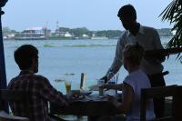 two men and a woman sitting at a table by the water at Ginger House Museum Hotel in Cochin