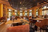 a restaurant with wooden tables and chairs and windows at Fletcher Boutique Hotel De Mallejan in Vierhouten