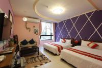 a bedroom with two beds and a purple wall at Kenting Diack Inn in Hengchun South Gate