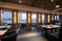 Un restaurante con mesas, sillas y ventanas. en Lumière Hotel Pool & SPA, en Belgrado