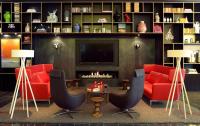 a living room with red furniture and a fireplace at citizenM Southwark Bankside in London