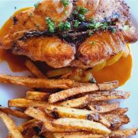 a plate of food with a chicken sandwich and french fries at Tiki Lodge Hotel de Charme in Santa Catalina
