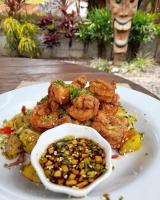 a plate of food with shrimp and corn and a sauce at Tiki Lodge Hotel de Charme in Santa Catalina