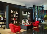 a library with two red chairs and books at citizenM Southwark Bankside in London