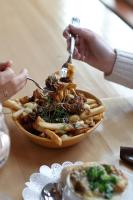 a person eating a bowl of food with a fork at Gîte du Mont-Albert - Sepaq in Sainte-Anne-des-Monts