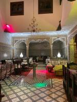 una habitación con un escenario, mesas y sillas en Riad Lahboul, en Meknès