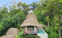 a small building with a thatched roof in a forest at Keemala in Kamala Beach