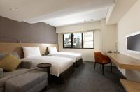 a hotel room with two beds and a couch at Royal Inn Taipei Linsen - Huashan 1914 Creative Park in Taipei