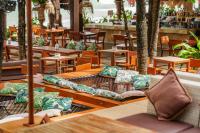 a restaurant with wooden tables and chairs with pillows at Café del Mar Phuket - Suite & Penthouse in Kamala Beach