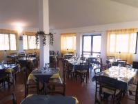 ein Esszimmer mit Tischen, Stühlen und Fenstern in der Unterkunft Nuraghe Ruiu Piazzole campeggio Blue Holiday in Norbello