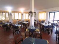 ein Esszimmer mit Tischen, Stühlen und Fenstern in der Unterkunft Nuraghe Ruiu Piazzole campeggio Blue Holiday in Norbello