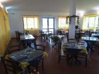 ein Esszimmer mit Tischen, Stühlen und Fenstern in der Unterkunft Nuraghe Ruiu Piazzole campeggio Blue Holiday in Norbello