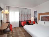 a hotel room with a large bed and red chairs at Novotel London West in London