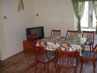 a dining room with a table and chairs and a tv at Babarczi Üdülőház in Kiskunmajsa