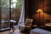 a bedroom with a bed and a chair and a balcony at Rong Unique Hotel-Banyan Lake Scenery in Guilin