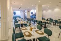 アル・ワジュにあるNeema Hotel Al Wajhの白いテーブルと緑の椅子が備わるレストラン