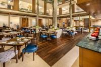 Un restaurante con suelos de madera y mesas y sillas azules. en Vivanta Goa, Panaji, en Panaji