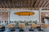 a surfboard hanging on a wall above a table and chairs at Suksma Guesthouse in Canggu