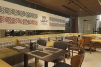 restauracja ze stołami, krzesłami i ścianą w obiekcie G Hotel Amman w mieście Amman