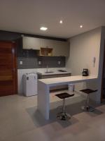 a kitchen with a counter and two bar stools at Pousada Studio Flat Jequié in Jequié
