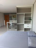 a bedroom with a bed and a desk and shelves at Pousada Studio Flat Jequié in Jequié