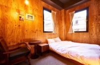 a bedroom with a bed and a chair and two windows at Focus Kuramae in Tokyo
