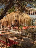 un restaurante con mesas y sillas y una sombrilla de paja en Bikini Island & Mountain Hotel Es Trenc -Adults only-, en Colonia de Sant Jordi