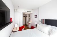 a white bedroom with a white bed and a red chair at citizenM New York Times Square in New York