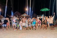 a group of people standing on the beach at night at Mad Monkey Hostel Nacpan Beach in El Nido