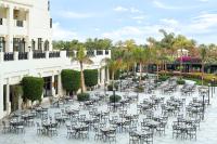 an outdoor patio with tables and chairs and palm trees at Steigenberger Aldau Beach Hotel in Hurghada