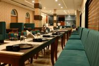 une rangée de tables dans un restaurant avec des chaises vertes dans l'établissement Royal Delight Resort, à Madīna