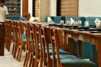 une longue table en bois avec un tas de chaises dans l'établissement Royal Delight Resort, à Madīna