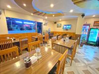 カトマンズにあるHotel Airport Holidayの木製のテーブルと椅子、そしてビデオゲームのあるレストラン