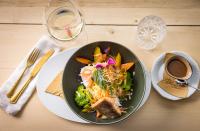 a plate of food with a salad and a cup of coffee at Hotel und Alpen Apartments mit Sauna - Bürglhöh in Bischofshofen