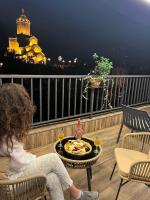una mujer sentada en un balcón con un plato de comida en Hotel Livin, en Tiflis