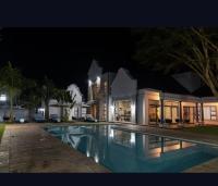 a house with a swimming pool at night at Ezulwini Villa hotel in Harare