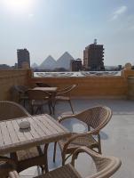 Un patio con mesas y sillas en un tejado. en Mirage pyramids view hotel, en El Cairo