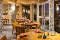 een restaurant met houten tafels en stoelen en ramen bij Carlina in La Clusaz