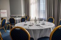a meeting room with tables and chairs with a bottle of wine at Ramada by Wyndham Belfast in Belfast