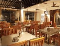a dining room with tables and wooden chairs at Hotel Nakshathra- A Royal Stay in Palani