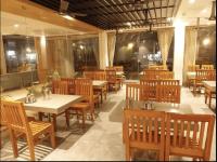 a restaurant with wooden tables and chairs and tables andermott at Hotel Nakshathra- A Royal Stay in Palani