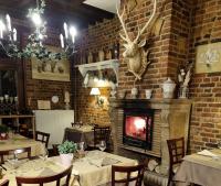 um restaurante com mesas e lareira em uma parede de tijolos em Auberge de la Forêt em Le Nouvion-en-Thiérache