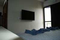 a bedroom with a bed with a television on the wall at Flat Sirena - São Vicente in São Vicente
