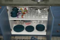 a kitchen cabinet with plates and dishes on a shelf at Flat Sirena - São Vicente in São Vicente