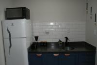 a kitchen with a sink and a white refrigerator at Flat Sirena - São Vicente in São Vicente